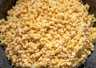 Soaked split mung beans in ceramic bowl on table, Top view