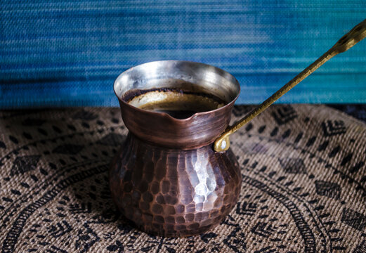 Handmade copper coffee mug with a brass handle on the background of decor made of natural materials.