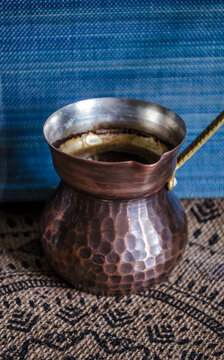 Handmade copper coffee mug with a brass handle on the background of decor made of natural materials.
