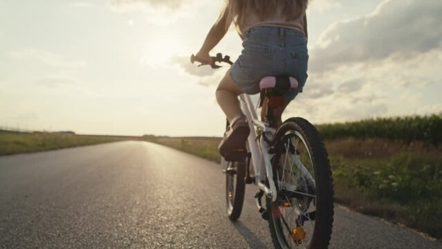 Close up of unrecognizable little caucasian girl riding a bike bike at sunset time. Shot with RED helium camera in 8K.  