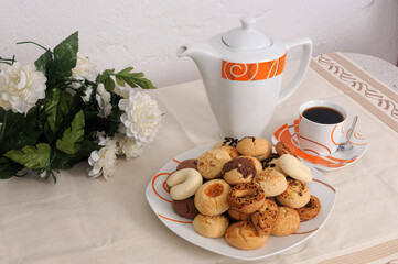 There is a pot of tea and homemade sweet cookies on the dining table.