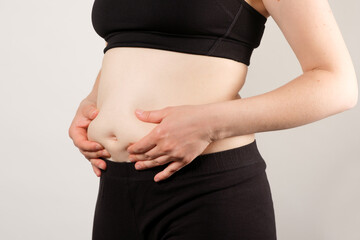 A woman shows an inflated thick belly, the concept of excess weight and weight loss.