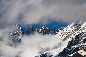 Clouds over the snow covered mountains. High mountains peak, winter landscape. 