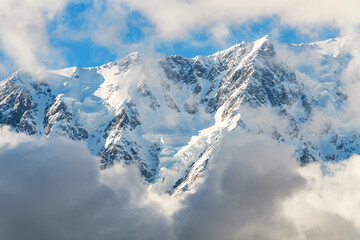 Obraz premium Clouds over the snow covered mountains. High mountains peak. Beautiful winter landscape.
