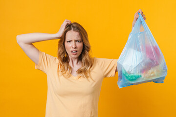 Young displeased woman wearing t-shirt posing with trash bag