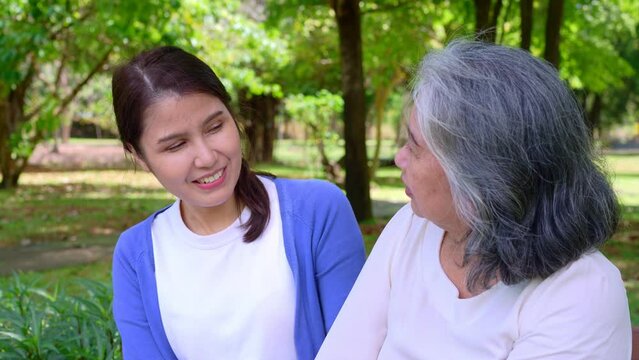 Happy senior mother with gray hair talk and laugh with daughter or caregiver in the park. Concept of happy retirement with care from a caregiver and Savings and senior health insurance, senior care