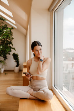 Young white woman using mobile phone during yoga practice