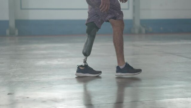 Disabled person walking with his prosthetic leg indoors. Amputee man walks with prosthetic leg
