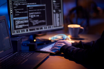 cybercrime, hacking and technology concept - close up of hacker in dark room writing code or using...
