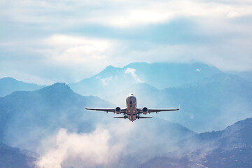 Fototapeta na wymiar jet flight travel concept stock photo. Airplane fly above amazing blue misty mountains
