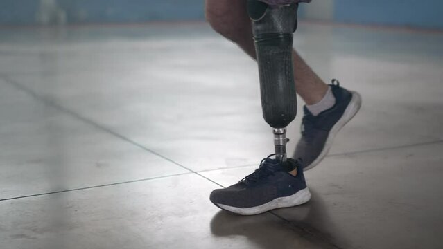 Disabled person walking with his prosthetic leg indoors. Amputee man walks with prosthetis legDisabled person walking with his prosthetic leg indoors. Amputee man walks with prosthetic leg