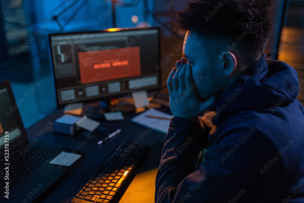 Poster cybercrime, hacking and technology concept - close up of male hacker in dark room using computer vir