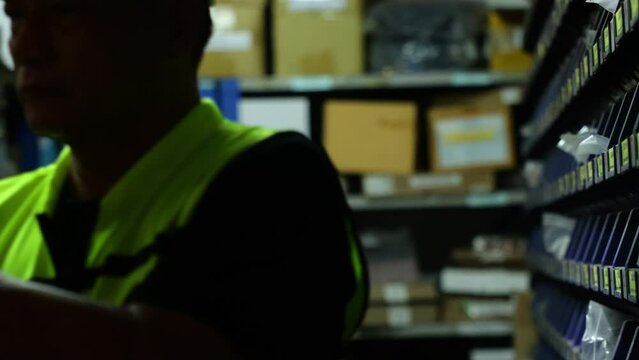 Security guard working at night. Senior asian male security working with flashlight at larg warehouse factory.