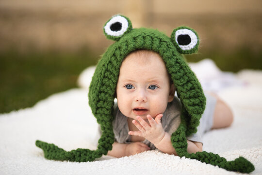 A girl in a frog's hat. A newborn baby in a frog costume. Photo session of newborns. Happy childhood.