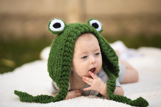 A girl in a frog's hat. A newborn baby in a frog costume. Photo session of newborns. Happy childhood.
