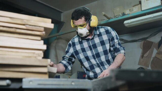 A man works with a planer. The carpenter uses personal protective . Craft