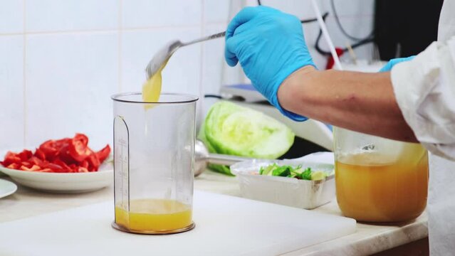 Chef preparing sweet sause with honey and orange juice in blender mix. Cooking avocado fresh salad, preparing ingredients in professional restaurant kitchen. Healthy and diet food delivery concept