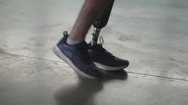 Disabled person walking with his prosthetic leg indoors. Amputee man walks with prosthetic leg