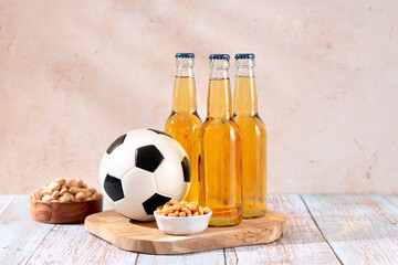 Beer and snack on wooden table with football ball, football game night food
