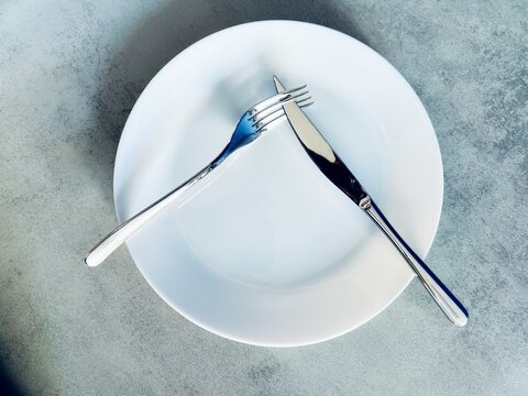 A fork and a knife arranged on a white clean plate