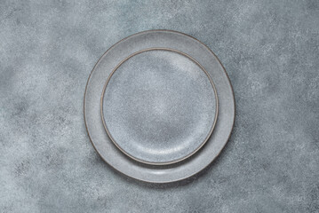 Empty gray plates on a gray stone background. Dishes for table setting. Top view, flat lay. Mock up with serving utensils.