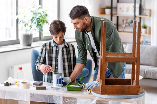 repair, diy and home improvement concept - father and son in protective gloves stirring grey color paint in can for painting old wooden table at home