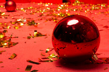 Close-up of a red large round Christmas ball with confetti background. Big red christmas ball. The...