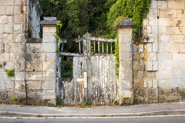 Derelict wooden gate in an old textured stone wall.