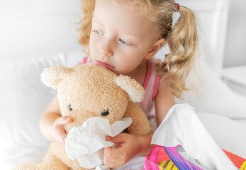 The child cleans the nose of the bear. Play during illness.