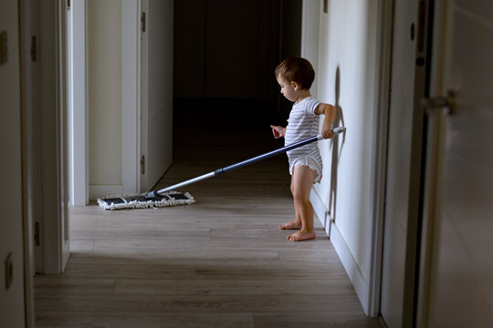 Ni&ntilde;o beb&eacute; limpiando la casa, pasando la mopa por el pasillo