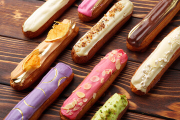 Assortment of sweet and colorful eclairs on wooden background