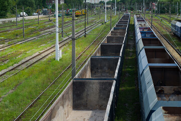 Empty blue coal railroad cars stand on a siding next to empty railroad tracks overgrown with grass