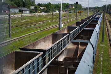 Empty blue coal railroad cars stand on a siding next to empty railroad tracks overgrown with grass