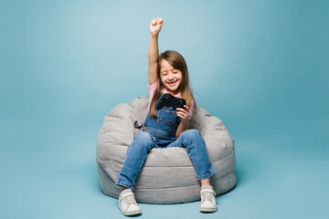 Excited girl winning on a video game against a blue background