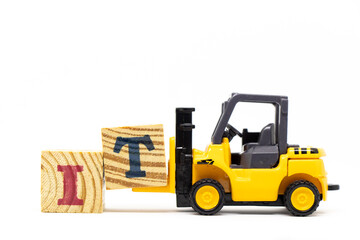 Toy forklift hold letter block T to complete word IT (Abbreviation of information technology) on wood background