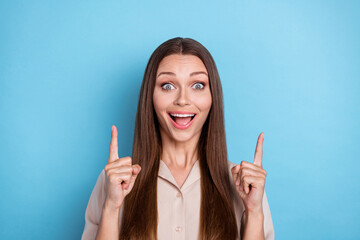 Photo of nice girlish lovely girl straight hairstyle wear beige blouse impressed directing empty space isolated on blue color background