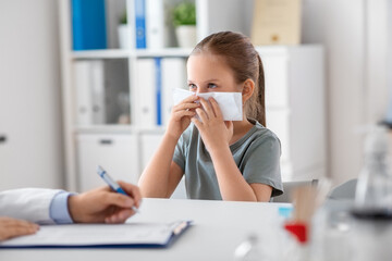 medicine, healthcare and pediatry concept - female doctor or pediatrician and little girl patient blowing her nose on medical exam at clinic