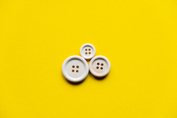 three wooden buttons of different sizes on a yellow background. family symbol