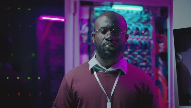 Portrait of African American network support engineer posing for camera in server room of data center