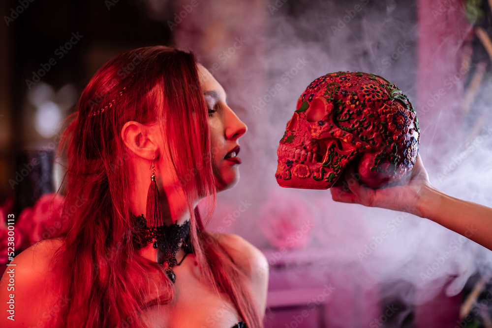 Wall mural a beautiful girl looks at a skull up close against a fog background