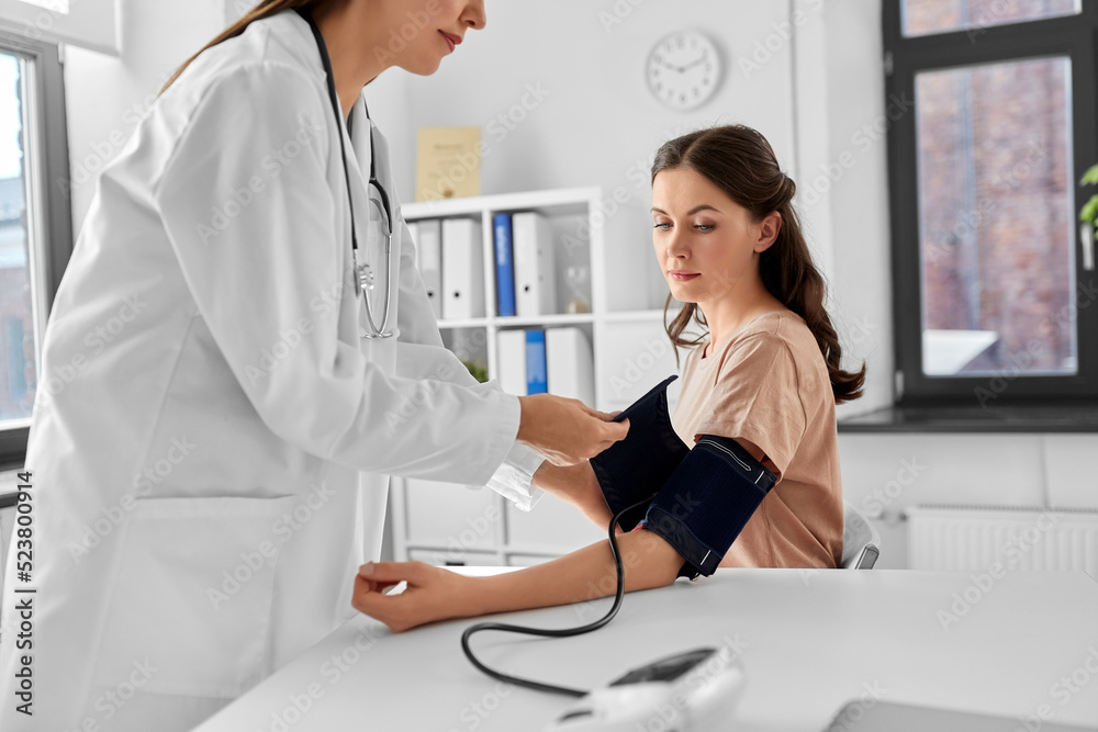 Wall mural medicine, healthcare and people concept - female doctor with tonometer measuring woman patient's blood pressure at hospital