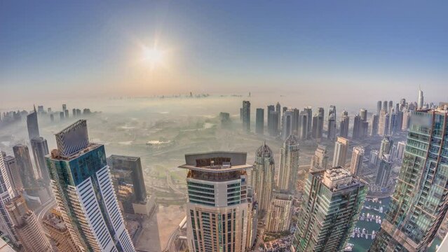 Panorama of Dubai Marina with JLT skyscrapers and golf course during sunrise timelapse, Dubai, United Arab Emirates. Aerial view from above towers foggy morning. City skyline with rooftops