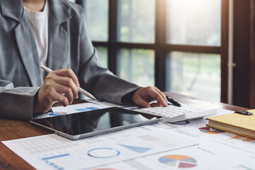 Business woman using calculator, tablet and documents to work