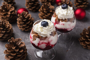 Trifle - traditional English dessert. Two portion in glasses on a dark stone table. Christmas and...