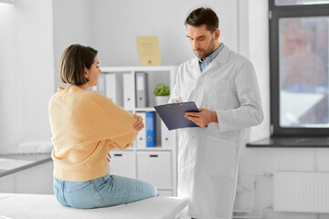 Obraz premium medicine, healthcare and people concept - male doctor with clipboard talking to woman showing her sore arm patient at hospital