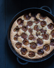 Homemade plum pie on a black background, top view
