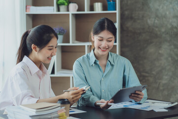 Obraz premium Two young Asian businesswoman discuss investment project working and planning strategy. Business people talking together with laptop computer at office.