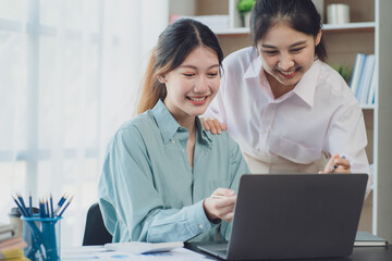 Two young Asian businesswoman discuss investment project working and planning strategy. Business people talking together with laptop computer at office.