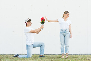 Pretty teenager girl rejecting flowers and proposal from boyfriend.