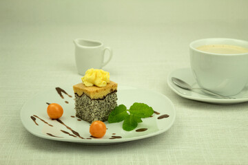 A piece of cake on a white plate and decorated with fruits and sauces